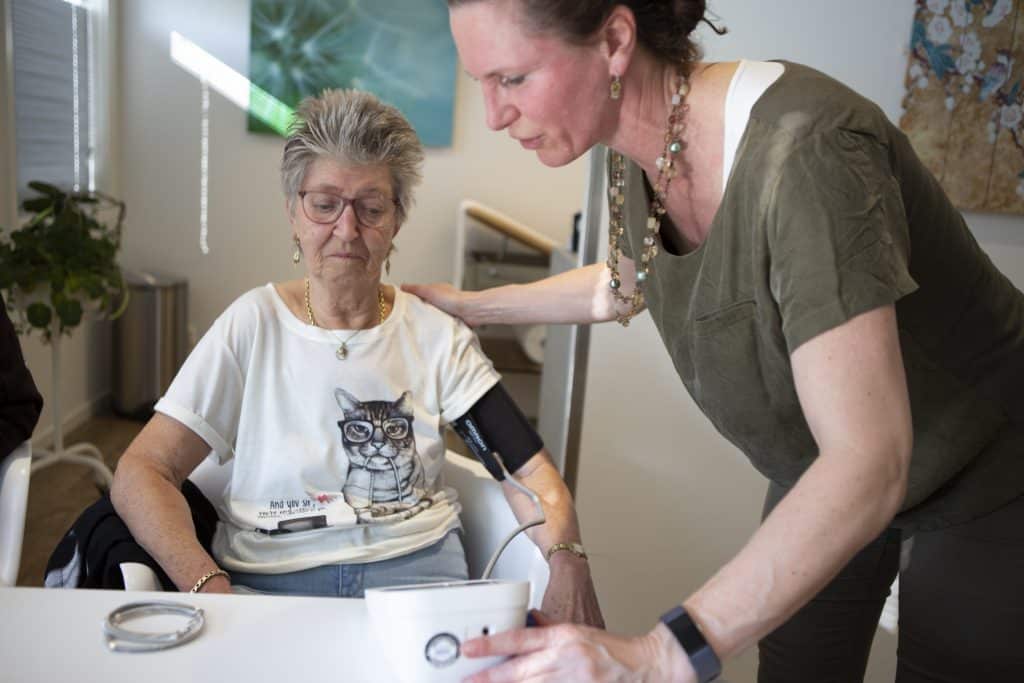 Huisarts helpt patiënt in rolstoel