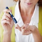 Vrouw met diabetes meet haar bloedsuiker met een prikpen.