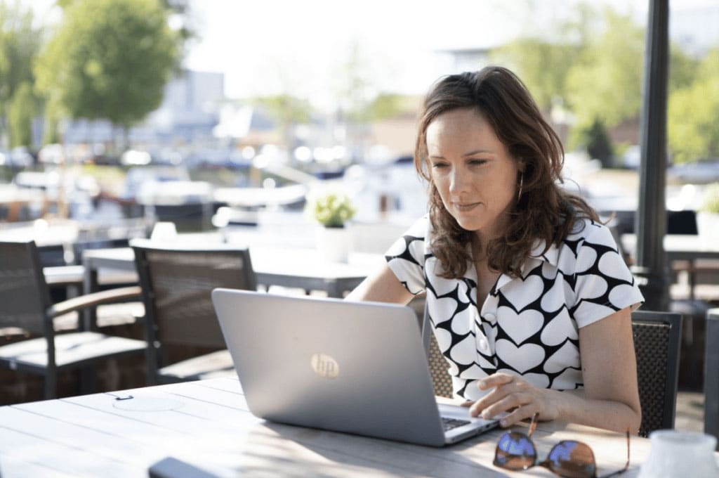 vrouw maakt een NHG E-learning op haar laptop op een terras
