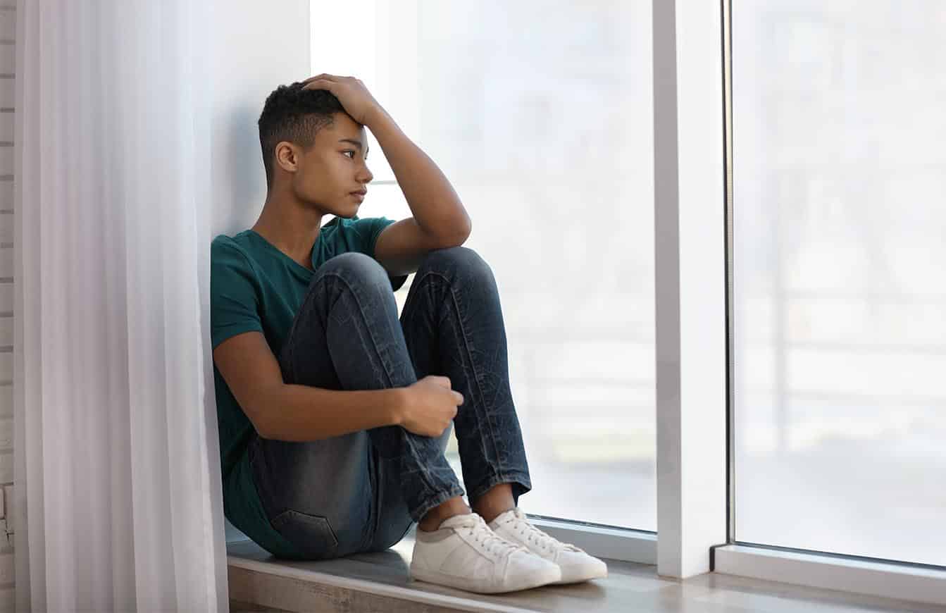 jongen kijkt depressief uit het raam