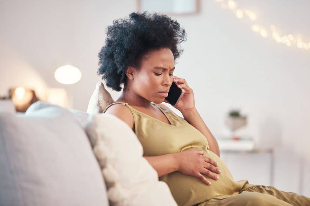 Bezorgde zwangere vrouw aan telefoon