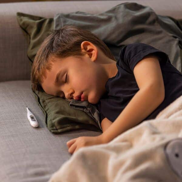 Slapend kind op de bank met thermometer naast zich.